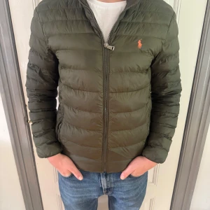 Olivgrön pufferjacka från Ralph Lauren - Tja! Säljer en olivgrön pufferjacka från Polo ralph lauren till ett skönt pris, finns små defekter men inget man märker av. Bara att hörs av sig vid funderingar. 