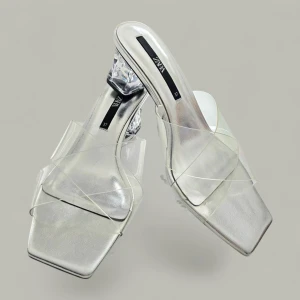 Silvriga sandaler med transparent klack Zara - Snygga sandaler från Zara i metallic silver med transparenta remmar och fyrkantig tå. Klacken är låg och i genomskinlig plast, vilket ger en futuristisk vibe. Perfekta för dig som vill sticka ut med en modern och trendig look.