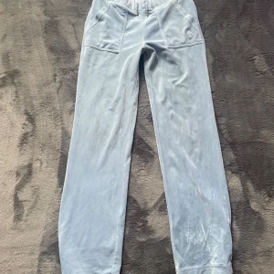 Ljusblå velourbyxor Juicy Couture XS - Supermjuka ljusblå mjukisbyxor från Juicy Couture i velour. Byxorna har snörning i midjan, två stora fickor fram och bakfickor med lock och bling-detaljer. Perfekta för en chill och trendig look.💙