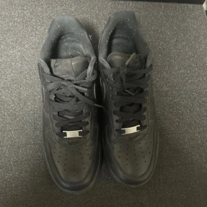 Nike Air Force 1 x supreme - Använda 2 gånger. Säljer ett par helsvarta Nike Air Force 1 Low i skinn med klassisk siluett och perforerad tå. Skorna har svarta snören och medföljer extra Supreme-senor för en unik touch. Perfekt för dig som gillar streetwear och vill ha en clean look.