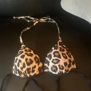 Leopardmönstrad och svart bikiniöverdel - Två bikiniöverdelar i trekantsmodell, en med leopardmönster och en i helsvart. Båda har knytband i nacken och ryggen. Tillverkade i syntetmaterial och polyester, perfekta för sommaren och bad. Helt nya, endast testade. 