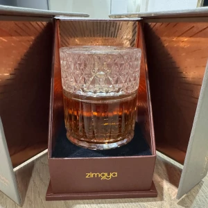 Sharaf Blend parfym från Zimaya - Lyxig parfym från Zimaya i en tung, kristalliknande glasflaska med guldlock. Doften heter Sharaf Blend och flaskan har ett elegant mönster och bärnstensfärgad vätska. Kommer i en exklusiv presentask med kopparfärgade detaljer.