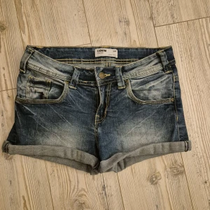 Blå jeansshorts från Denim Inside - Klassiska blå jeansshorts från Denim Inside med upprullade benslut och slitna detaljer. Shortsen har fem fickor och synliga kontrastsömmar. Perfekta för varma dagar och enkel att matcha med olika toppar.🌺☀️