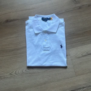 Vit piké från Polo Ralph Lauren - Klassisk vit pikétröja storlek M från Polo Ralph Lauren med broderad logga på bröstet. Tröjan har krage, knappar och är i modellen custom slim fit. Perfekt för en stilren look. I ny skick och näst intil oanvänd. Pris kan diskuteras vid snabb förhandling