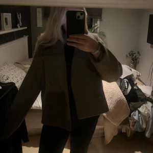 Brun skepparkavaj i ull - Snygg brun skepparkavaj med bred krage och dubbelknäppning. Jackan är croppad och har raka ärmar samt två fickor framtill. Perfekt för dig som gillar klassisk stil med en modern twist.