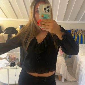 Svart blus med volang och v-ringning - Svart blus från Zara med transparenta långärmar och v-ringning. Blusen har volangdetaljer längs halsen. Storlek S💕