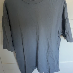 Grå oversized t-shirt från FSBN - Snygg grå t-shirt från FSBN i oversized passform. T-shirten har rund hals och korta ärmar, tillverkad i mjuk bomull. Enkel och clean design som funkar till jeans eller shorts. Perfekt för dig som gillar en loose och chill stil. Använd 1 gång och tvättas innan den skickas