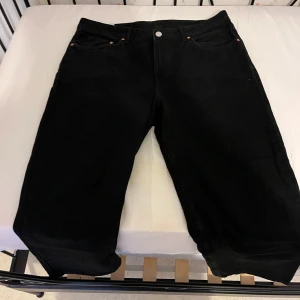 Svarta Levis 501 jeans straight fit - Klassiska svarta Levis 501 jeans med raka ben och femficksmodell. Jeansen har knappgylf och är tillverkade i kraftigt denimtyg. Perfekta för dig som gillar en tidlös och clean look.