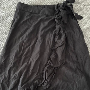 Svart omlottkjol från Lindex - Svart omlottkjol från Lindex med snygg knytning i midjan (går att göra midjan mindre) Kjolen är tillverkad i mjuk bomull,pris går att diskutera, väldigt fin🖤