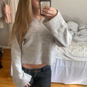 Ljusgrå croppad stickad tröja - Supermysig ljusgrå stickad tröja med croppad passform och breda ribbade muddar. Storlek 146/152