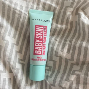 Maybelline Baby Skin Primer - Maybelline Baby Skin Instant Pore Eraser är en primer i en mintgrön tub med rosa och vit text. Den ger en silkeslen känsla och suddar ut porer för en jämnare bas. Tuben innehåller 22 ml och är perfekt att använda innan foundation för en flawless look.