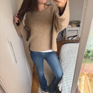 Beige stickad tröja från Weekday - Mysig beige stickad tröja från Weekday i storlek S. Tröjan har en loose passform, breda ärmar och ribbade muddar vid hals, ärmslut och nederkant. Perfekt för lager-på-lager och chill dagar.