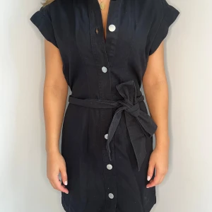 Svart kort klänning från Monki XS - Svart kort klänning från Monki i linne med knappar framtill och ett brett knytbälte i midjan. 🥰
