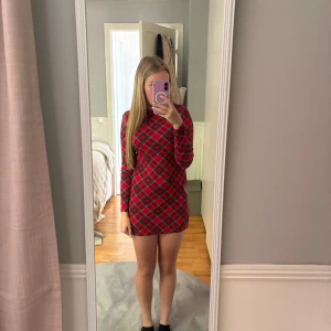 Julklänning - Säljer en röd klänning med svart, grön och vit rutig design. 