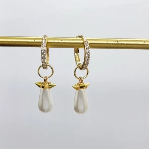 Silver 925 örhängen med pärldroppar - Snygga örhängen i guld med gnistrande stenar på ringen och droppformade vita pärlor som hänger i små guldfästen med coola spetsdetaljer. Perfekt för dig som vill ha något unikt och glittrigt till din look.