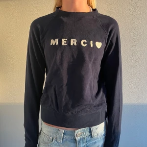 Mörkblå sweatshirt med text MERCI - Mörkblå sweatshirt med vit text 'MERCI' och hjärta framtill. Tröjan har rund halsringning och långa ärmar. Skön passform och tillverkad i mjuk bomull. Nypris: 349kr. Använd men märks bara på insidan pga tvätt 💞💞