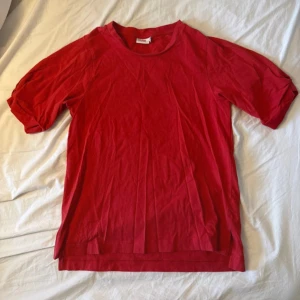 Röd t-shirt med kort ärm - En enkel röd t-shirt med rund hals och korta ärmar. T-shirten är gjord i mjuk bomull och har en clean look utan mönster eller tryck. Perfekt för dig som gillar basic och stilrena plagg. Snygg att matcha med jeans eller shorts.