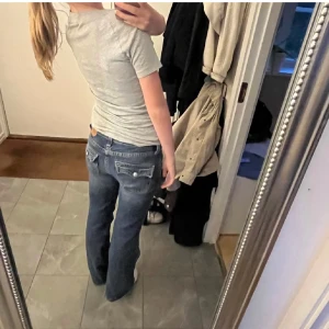 Levi's Noughties Bootcut jeans blå - Snygga blå Levi's Noughties Bootcut jeans med klassiska fickor bak och vita knappar. Bootcut-modell med låg midja och raka ben. Jeansen är i denim med coola detaljer och passar perfekt till sneakers eller boots. Är lite slitna längs ner men det är för att Levis affären lagt ner dom