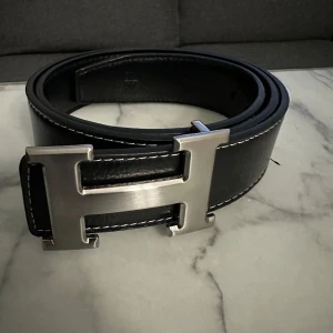 Herrmes bälte med H-spänne - Svart Herrrmes bälte med silvrig H-spänne för endast 275 kr. Ingen synlig tecken på användning, använts ett få par gånger. 