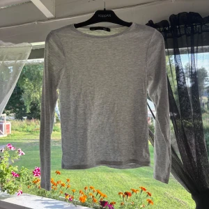 Ljusgrå långärmad tröja från lager 157 - En enkel och stilren ljusgrå långärmad tröja från lager 157. Tröjan har rund halsringning och är gjord i mjuk bomull, perfekt för chill dagar eller när du vill ha en clean look. Passformen är normal och materialet känns lätt mot huden.