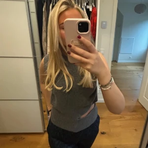 Grå ärmlös stickad topp med cut out - Säljer en grå ärmlös stickad topp med cut out-detalj vid midjan från Zara.