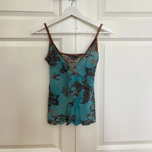 Turkos och brun topp från Gina Tricot - Säljer denna jättesöta toppen som jag hittat second hand men är originellt från Gina Tricot. Toppen har omlott-skärning framtill, bruna kanter och en liten knytning i midjan, så söt men tyvärr för liten för mig. Perfekt för dig som gillar unika detaljer och lite y2k vibes.❤️