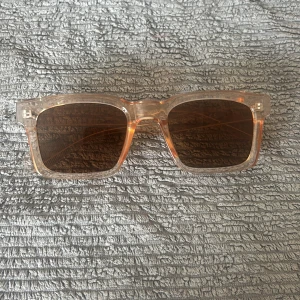 Rektangulära solglasögon i transparent beige - Snygga solglasögon med rektangulära linser och transparent beige plastbåge. Glasen är bruna.