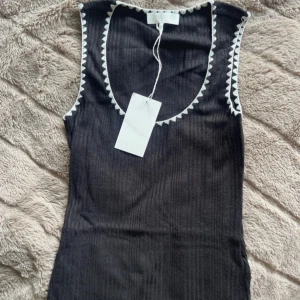 Svart ribbad linnetopp från NA-KD - Svart ribbad linnetopp från NA-KD i storlek XS. Plagget är helt nytt och prislapp sitter kvar!