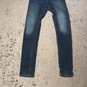  Diesel jeans slim fit - Snygga blå jeans från Diesel med klassisk femficksdesign och slim fit  passform. Jeansen har en mörk tvätt med lätt slitning på låren och kontrastsömmar. Perfekta för dig som gillar en smal siluett och vill ha ett par stilrena jeans i garderoben. W29 L32