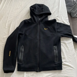 Svart Nike NOCTA kofta - Svart vindjacka från Nike NOCTA med huva och hel dragkedja. Jackan har gula detaljer, två fickor med dragkedja och en clean, sportig look. Perfekt för dig som gillar streetwear och vill ha något stilrent och funktionellt. Sitter tight som M, så passar även S. Passer en som är 173 ungefär. Pris kan diskuteras❗️