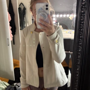  vit kappa med guldknappar - Säljer en snygg vit kappa med guldiga knappar vid hals och ärmslut. Jackan är så stilren o elegant hör av er vid frågor!!🩷🩷