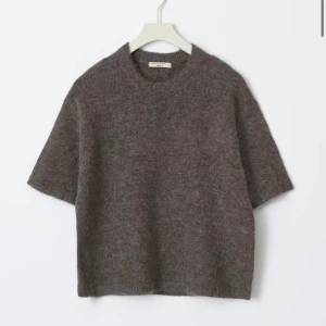 Brun stickad tröja från Ginatricot  - Mjuk och stilren brun stickad tröja från Totême med korta ärmar och rund hals. Tröjan har en loose passform och är tillverkad i ett fluffigt material som känns lyxigt och skönt mot huden. Perfekt för lager-på-lager under hösten och vintern.