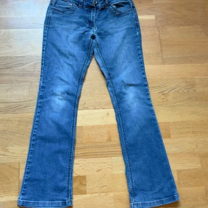 Blå bootcut jeans Authentic Denim - Snygga blå jeans från Authentic Denim med klassisk bootcut passform. Jeansen har coola kontrastsömmar på bakfickorna och en lätt tvättad look. Tillverkade i mjukt denimtyg som sitter skönt hela dagen. Mid waist byxor med lite mer år de low waist hållet, Pris kan diskuteras.