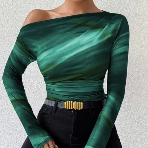 Turkos omlott topp med drapering - Säljer en snygg turkos omlott topp med draperad effekt och lång ärm. Toppen har ett coolt mönster i olika blå och gröna nyanser, med en unik omlott-detalj vid halsen. Perfekt för dig som gillar färg och vill sticka ut.