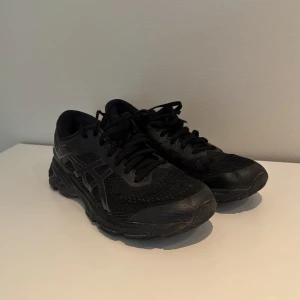 Svarta Asics sneakers strl 40 - Svarta Asics sneakers med mesh- och syntetöverdel, klassisk Asics-logga på sidan och snörning. Snygg sportig vibe med robust sula i gummi, perfekt för dig som gillar stilrena träningsskor. Modellen är låg och passar dig som vill ha bekväma skor till vardagen.