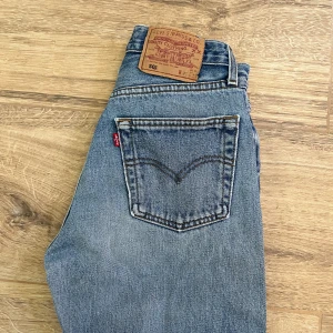 Levi's 501 blå jeans straight fit st 27 - Klassiska Levi's 501 jeans i blå denim med raka ben och femficksmodell. Snyggt slitna detaljer och ikonisk läderpatch bak i midjan. Perfekta för dig som gillar tidlös stil och vill ha ett par jeans som funkar till allt.