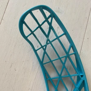 Zone klubba  - Bilderna visar en innebandyklubba med blått blad och vitt skaft. Den är lätt och passar perfekt för snabba matcher och träning. Greppet är lindat med blå tejp för extra komfort. Perfekt för dig som vill ta ditt spel till nästa nivå!