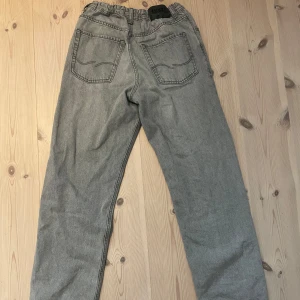 Gråa loose fit jeans från Jack and Jones - Säljer ett par gråa jeans från Acne Studios med klassisk femficksdesign och raka ben. Jeansen har en loose fit och hög midja, perfekt för en avslappnad och trendig look. Materialet är robust denim och färgen är snyggt tvättad grå.