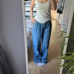 Wide jeans från Pull&Bear, blå, strl 38 - Säljer ett par blå jeans från Pull&Bear i storlek 38. De har en loose och wide passform med hög midja och raka, vida ben. Klassisk femficksmodell i jeansmaterial, perfekt för en avslappnad och trendig look. (insydda i midjan)