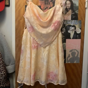 Blommig kortklänning från Boohoo - Superfin kortklänning från Boohoo i ljusa toner med blommigt mönster i rosa och vitt. Klänningen har draperad urringning, breda axelband och volangdetaljer längs sidorna. Perfekt för sommarens alla tillfällen!