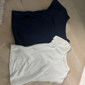 2-pack Shein toppar vit & marinblå  - Två basic toppar från Shein i storlek XXS, en i klassiskt vitt och en i marinblått. Båda har rund halsringning och kort ärm, tillverkade i mjuk och stretchig polyesterblandning. Perfekta att matcha med jeans eller kjol för en clean look.