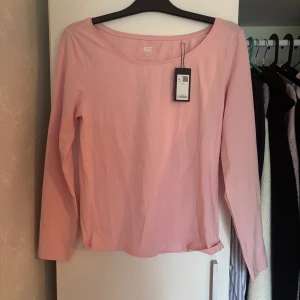 Ljusrosa långärmad tröja 157 - Enkel och stilren ljusrosa långärmad tröja från 157. Tröjan har rund halsringning och är gjord i mjuk bomull, perfekt för en chill och avslappnad look. Passar lika bra till jeans som till mjukisbyxor. Färgen ser annorlunda ut på första bilden än på andra det är för att på första bilden så var den i skuggan. Ordinarie pris 60kr men säljer den för 50kr. Har inte använt den alls 