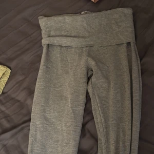 Grå mjukisbyxor med bootcut från Gina tricot  - Grå mjukisbyxor med bred, vikt midja och bootcut-ben. Sköna och stretchiga, perfekta för chill dagar eller när du vill vara bekväm men ändå ha stil. Tunt och mjukt material som känns riktigt nice mot huden.