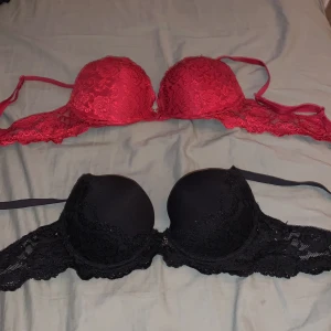 2 spetsiga push-up bh:ar svart & röd - Säljer två snygga push-up bh:ar från Cubus, en i svart och en i rött. Båda har spetsdetaljer över kuporna och på sidorna, vilket är väldigt fint. Justerbara axelband och vadderade kupor för extra lyft. Perfekt för dig som gillar spets och vill ha något som sticker ut. Den röda är i storlek 75A  och den svarta är i storlek 70B. Det är några fläckar i den svarta som inte går bort i tvätten men går ju såklart att använda ändå, den svarta är ganska använd men den röda är bara använd nån gång.
