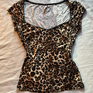 Leopardmönstrad topp från Nelly XS - Säljer en figurnära topp från Nelly i storlek XS med leopardmönster i svart och beige. 