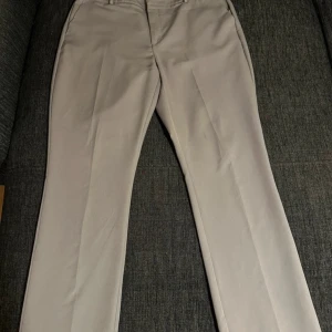 Gråa kostymbyxor - Snygga gråa kostymbyxor. Byxorna har hällor för bälte och två fickor bak. Perfekta för en clean och stilren look. Materialet känns mjukt och har en lätt stretch för extra komfort.