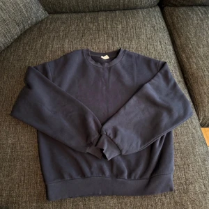 Mörkblå basic sweatshirt - Enkel och stilren mörkblå sweatshirt med rund hals och långa ärmar. Tröjan har ribbade muddar vid ärmslut och nederkant, perfekt för en chill och avslappnad look. Passar dig som gillar klassiska och bekväma plagg.