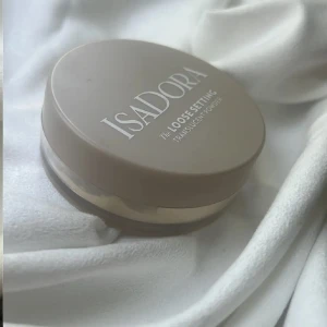 Isadora Loose Setting Powder Translucent - Isadora Loose Setting Powder i färgen 00 Translucent. Ett transparent, veganskt och parfymfritt puder i rund burk med beige lock. Perfekt för att fixera sminket och ge en matt finish utan att kännas tungt. Innehåller 9g och är tillverkad i Sverige.