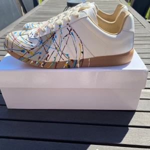 Maison Margiela skor färgstänk vit - Maison Margiela färgstänk sneakers i vitt med färgstänk i blått, gult, rött och svart. Ett utmärkt val nu till sommaren. Jag har digitalt kvitto. Inga byten. Hör av vid frågor!