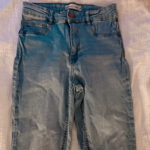 Ljusblå jeans  - Säljer ett par ljusblå jeans med klassisk femficksdesign och normal passform. Jeansen har en snygg tvättad look och är tillverkade i mjukt bomullsmaterial. Perfekta för en avslappnad stil.